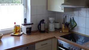 Una cocina equipada con lavavajillas, horno, cafetera, hervidor y una ventana con vistas a árboles.