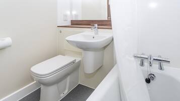 Une salle de bain avec des toilettes, un lavabo et une baignoire.