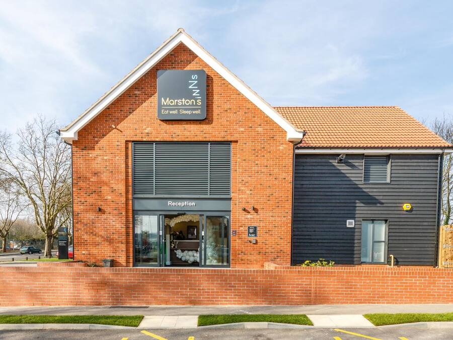Un hotel Marston's con una zona de recepción, fachada de ladrillo y una extensión de color oscuro.
