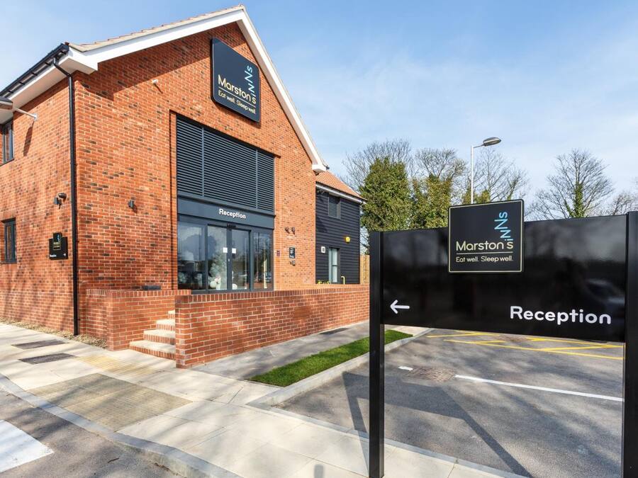 A brick building with a reception area, a sign indicating 'Marston's', and a directional arrow pointing to the reception.