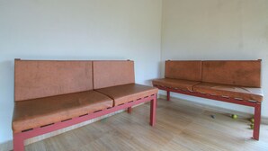 Huoneessa on kaksi punaista penkkiä, joissa on pehmustetut istuimet. Huoneen lattia on puuta ja seinät ovat valkoiset.