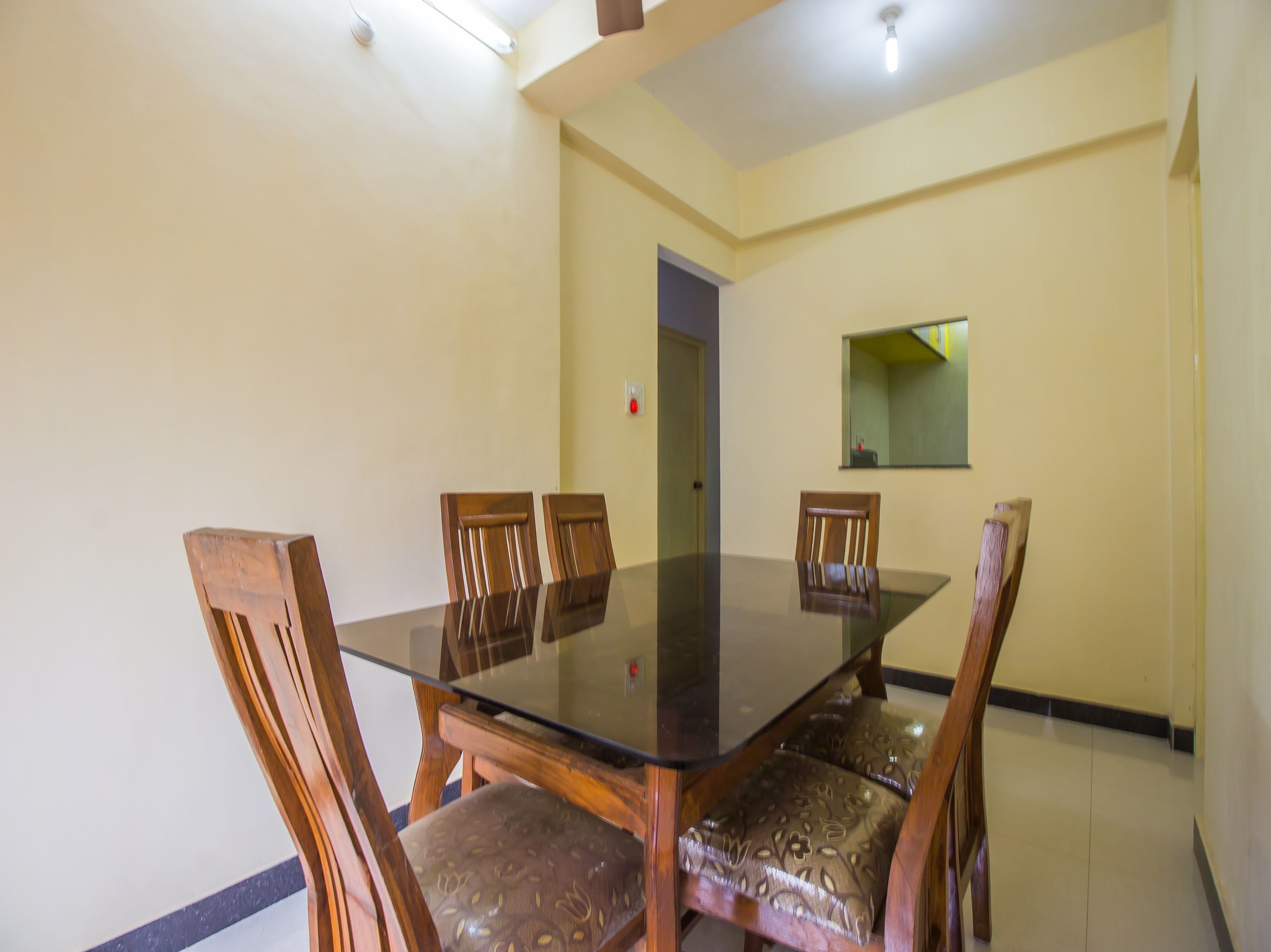 A dining area with a glass-top table and wooden chairs.