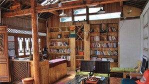 Um interior rústico em madeira com uma mesa central, estantes e um espaço de estar.
