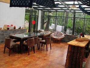 A dining area with a glass table, chairs, and a wooden bench. - Pure Yard (Lijiang)