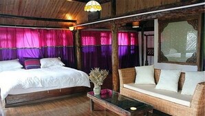 Um quarto com uma cama, um sofá de vime e uma mesa com um vaso.