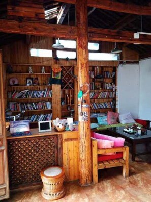 A rustic wooden room with a bookshelf, a desk, and a bench. - Pure Yard (Lijiang)