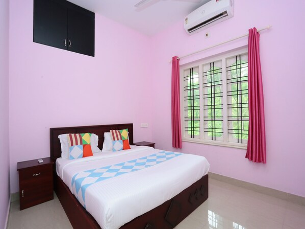 A bedroom with a bed, nightstands, a wardrobe, a window with curtains, and an air conditioning unit. - OYO 15916 Home Cozy 2BHK Kalpetta (Vythiri)