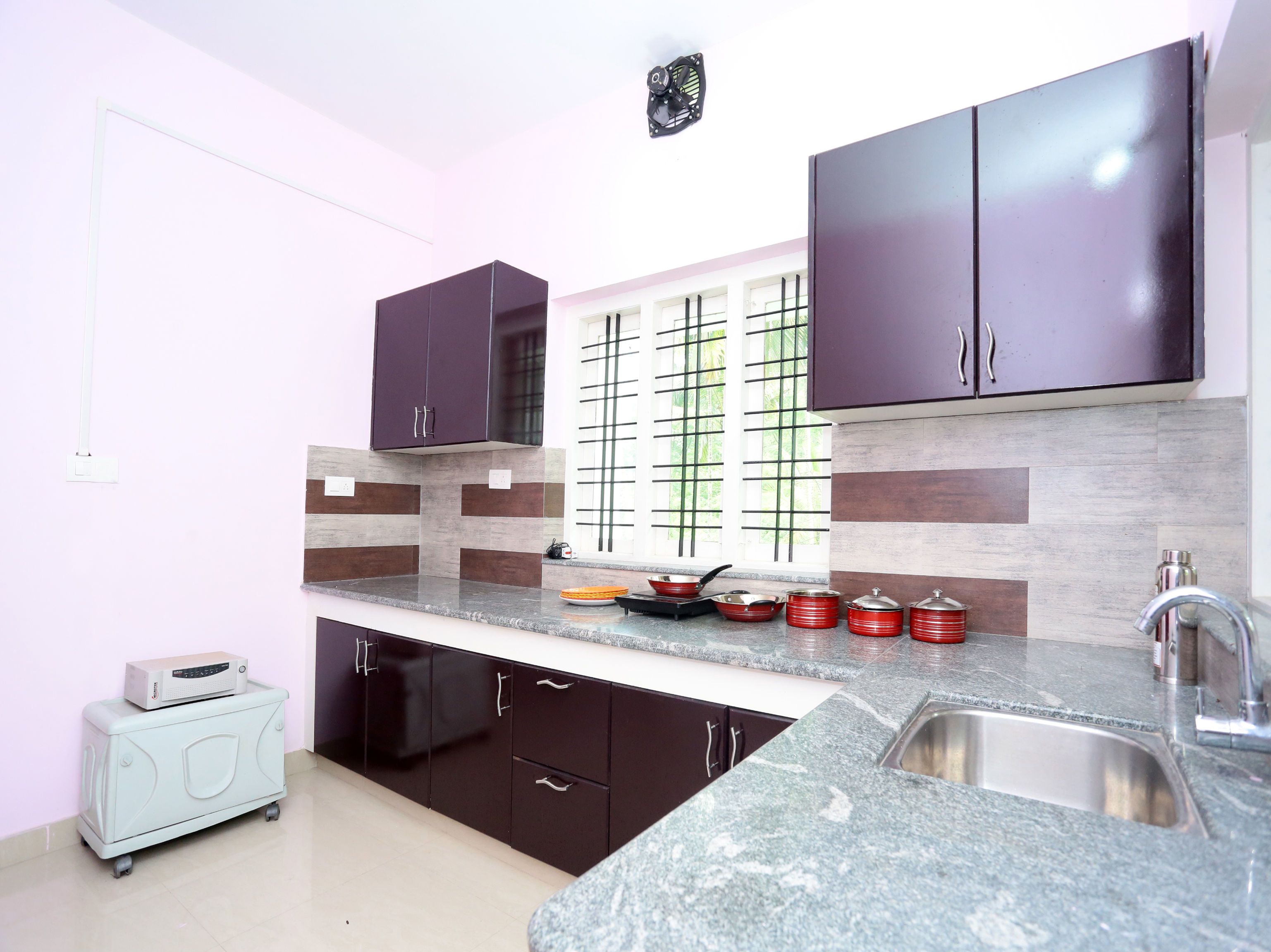 A modern kitchen with dark cabinets, a granite countertop, and a window with a grid pattern.