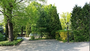 Un chemin pavé dans un parc, bordé d’arbres et éclairé par un lampadaire.