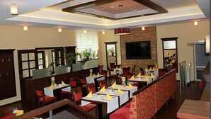 Un restaurant doté de nombreuses tables et chaises, d’un bar et d’une cheminée.