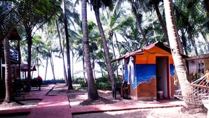 A pathway leading to a small building with a colorful mural, surrounded by palm trees.
