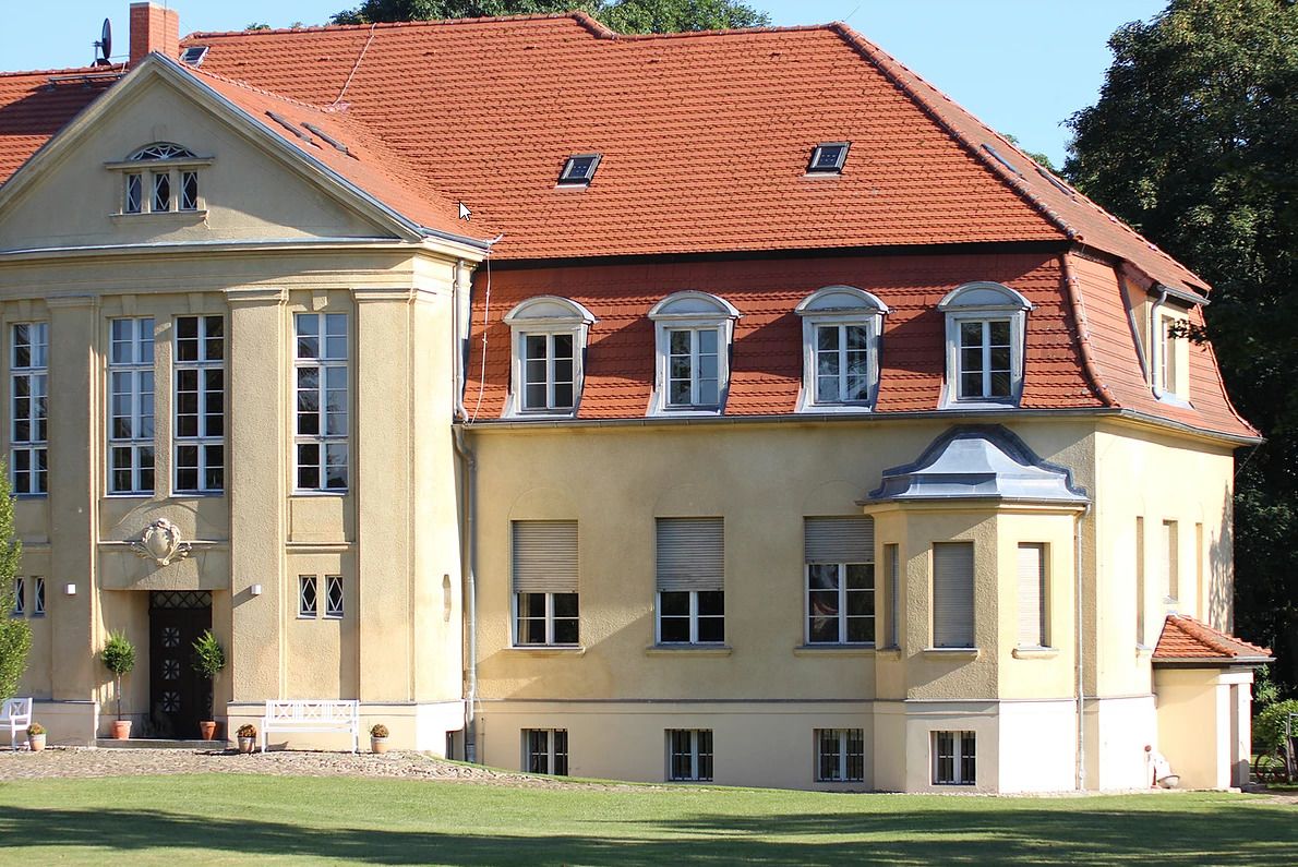 Ein großes, zweistöckiges Gebäude mit rotem Ziegeldach und einer symmetrischen Fassade.