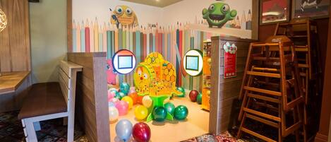 A children's play area with colorful decorations, a table, chairs, and a ladder.