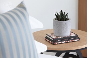 A round wooden table with a grey pot containing a plant, placed on top of a stack of books with floral patterns.