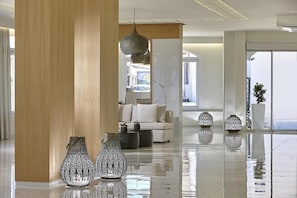 Een moderne lobby met een witte bank, decoratieve vazen en een grote houten kolom.