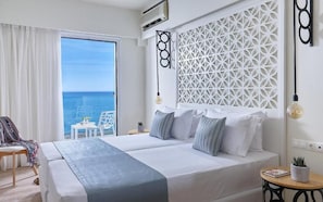 Een hotelkamer met een groot bed, uitzicht op zee, een decoratief paneel en een tafeltje met een plant.
