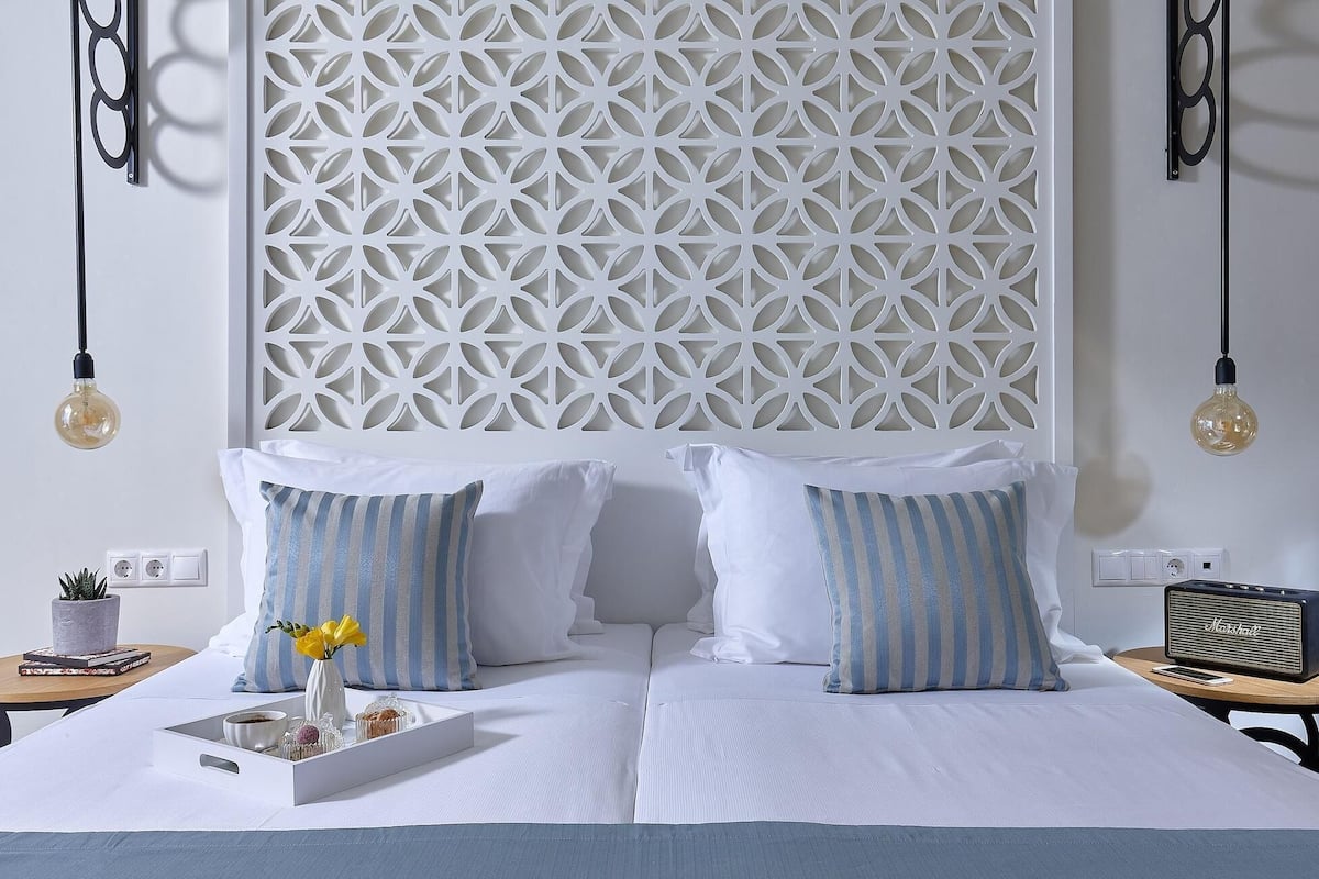 Een netjes ingerichte hotelkamer met een bed, kussens, een nachtkastje, een radio en een decoratief wandpaneel.