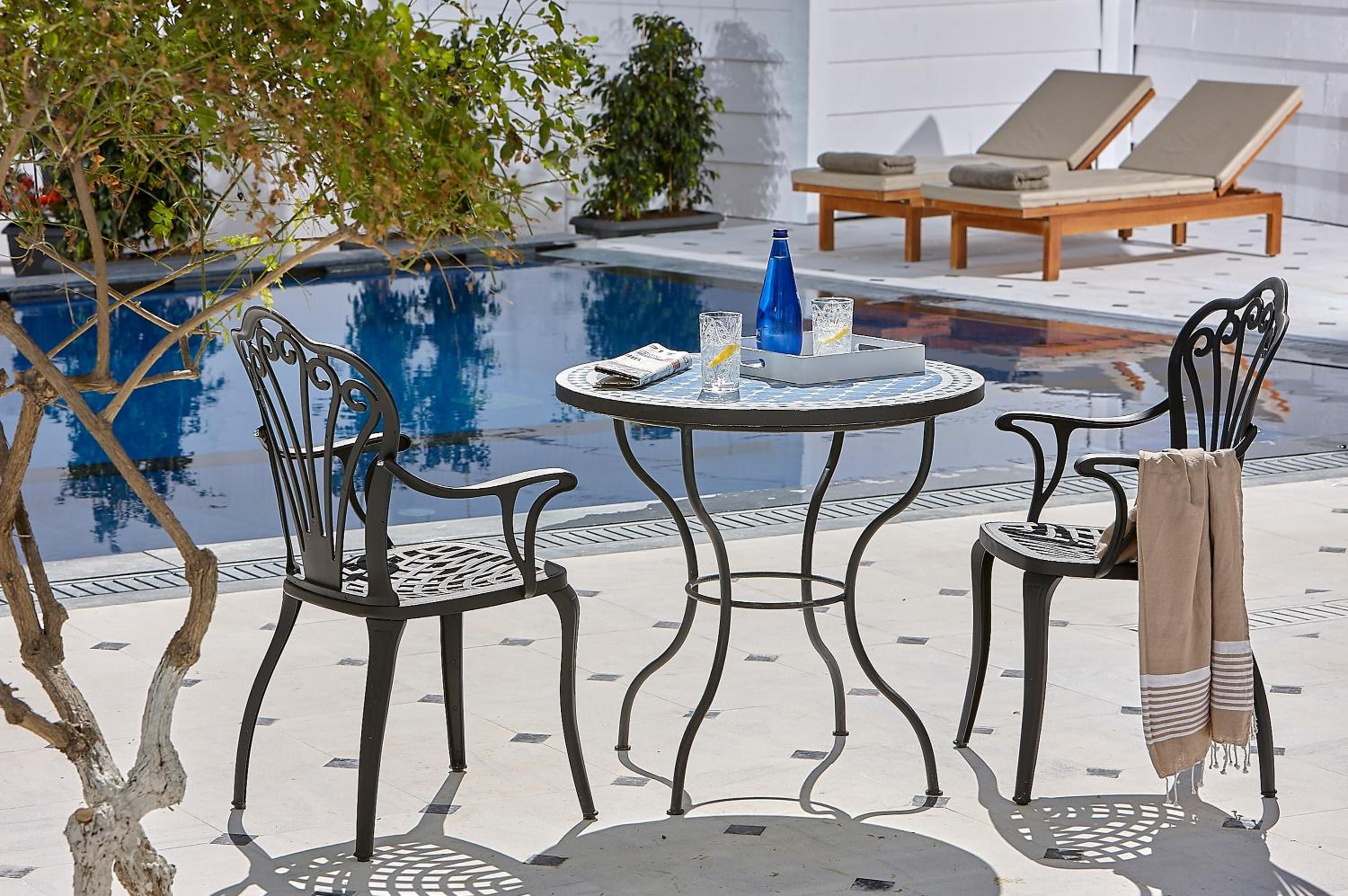 A poolside area with two lounge chairs, a table with drinks, and a small pool.