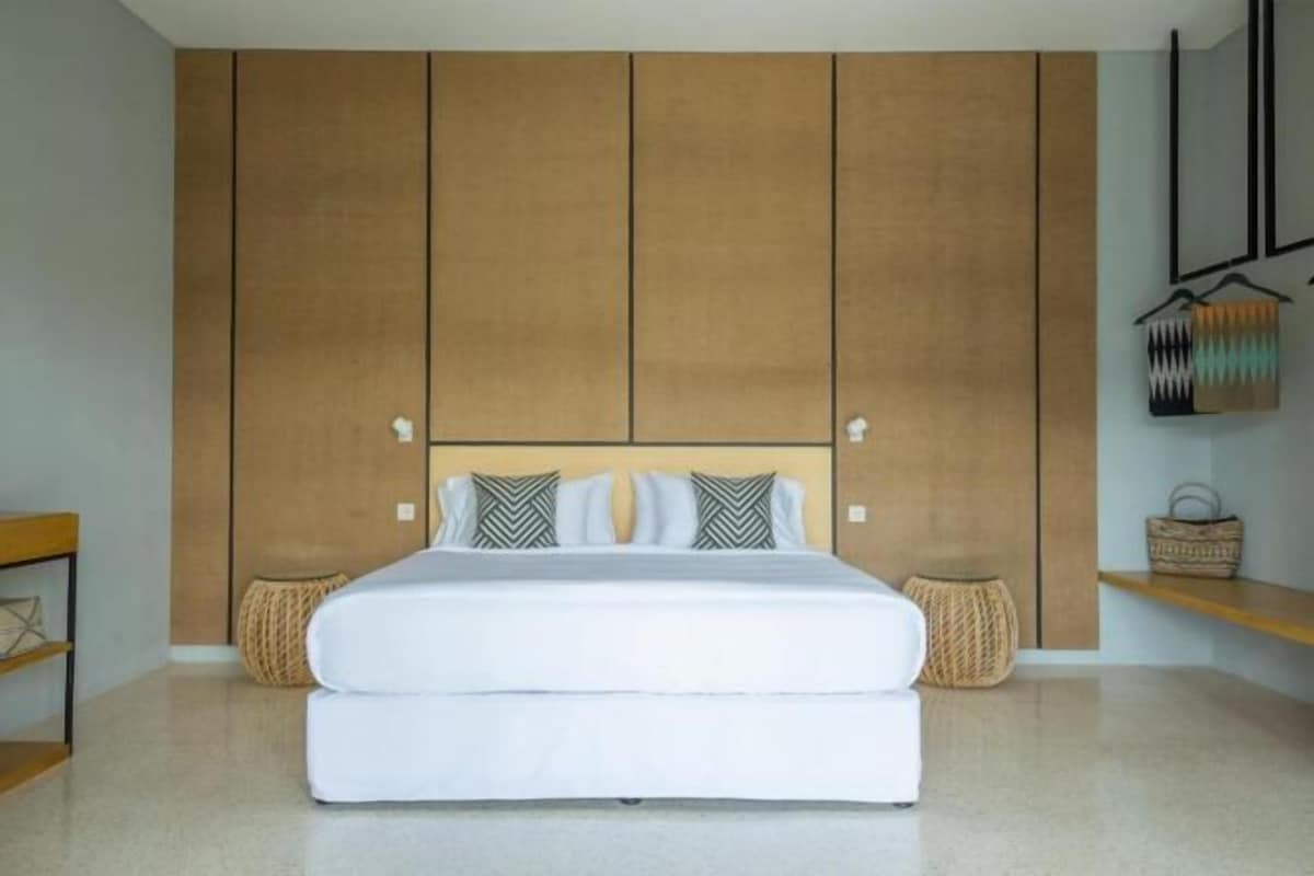 A bedroom with a large bed, wooden panel walls, and a small side table.