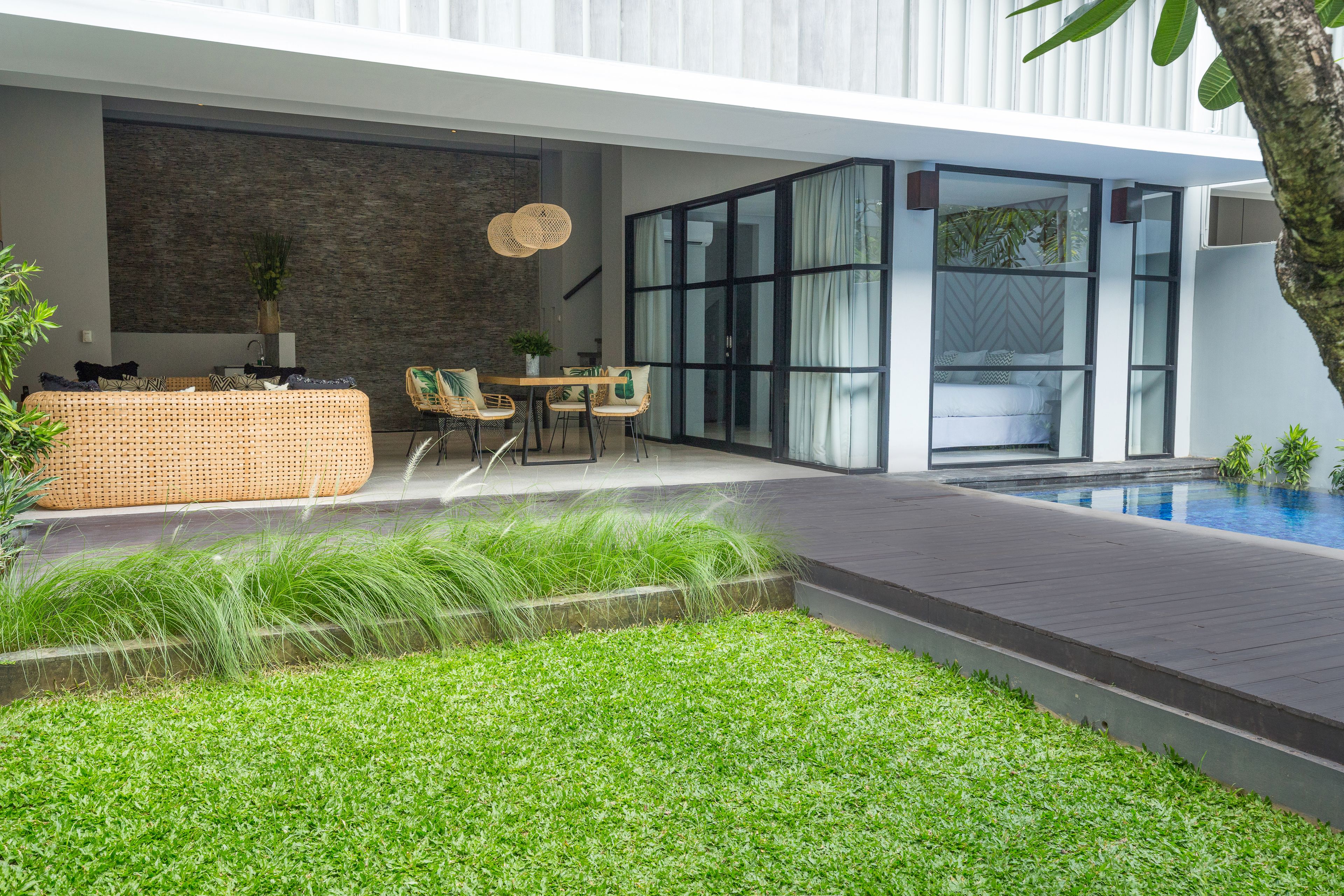 A modern outdoor patio with a dining area, a pool, and a well-maintained lawn.