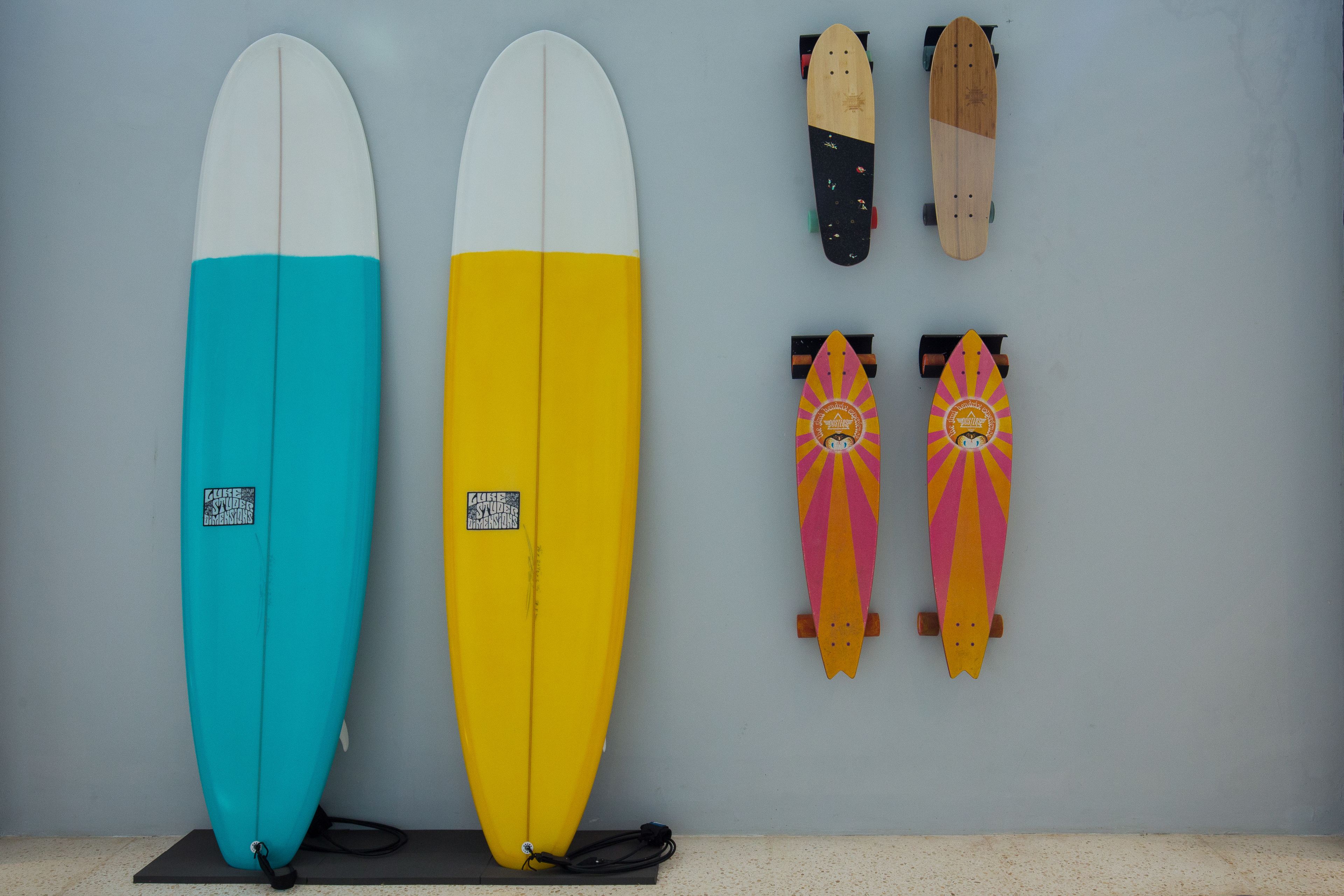 Two surfboards and two skateboards against a wall.