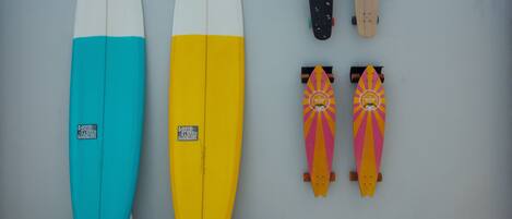 Two surfboards and two skateboards against a wall.
