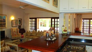 Un salon spacieux avec une grande table basse en bois, un canapé et un téléviseur. Il y a également un coin cuisine équipé d’une cuisinière et de placards.