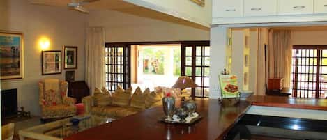 Amplia sala de estar con una gran mesa de centro de madera, un sofá y un televisor. Cuenta con una zona de cocina con estufa y alacenas.