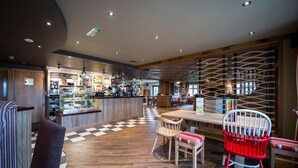 Un restaurante con piso a cuadros, muebles de madera y una zona de bar con vitrina.