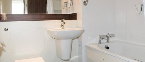 A modern bathroom with a toilet, sink, and bathtub.