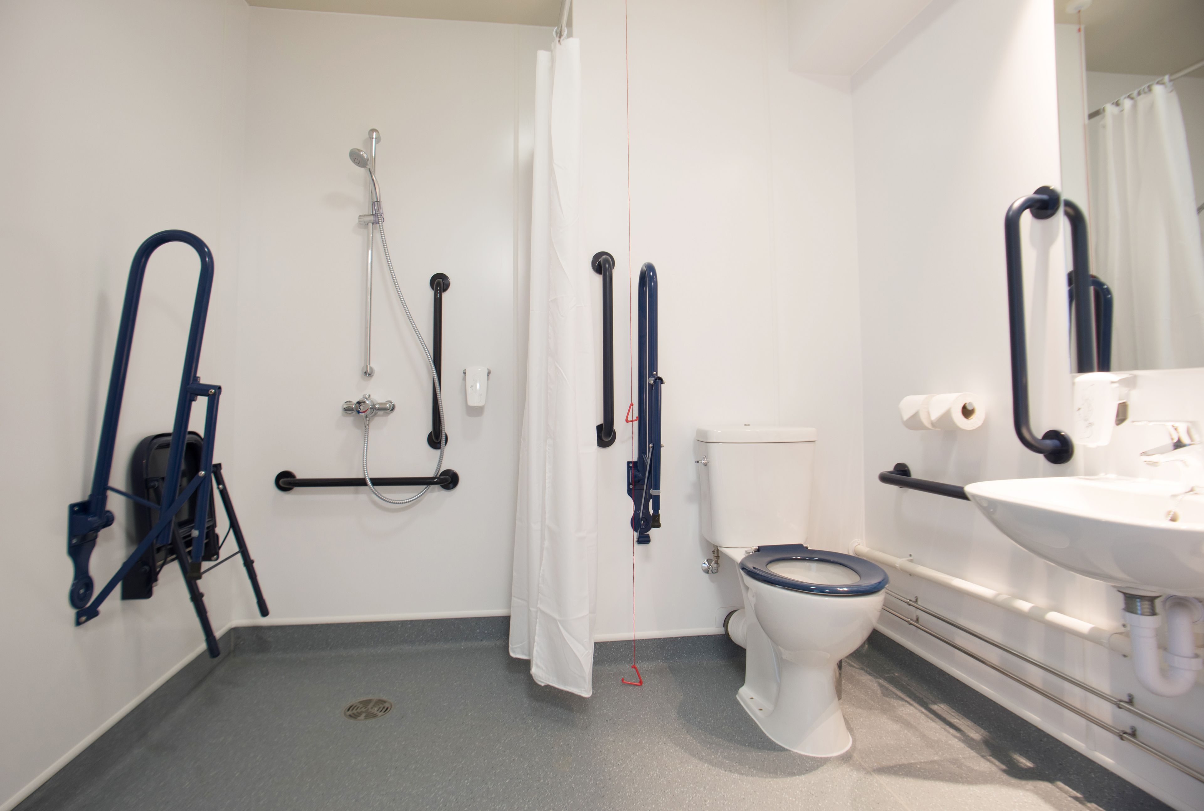A bathroom with a toilet, shower, and sink.