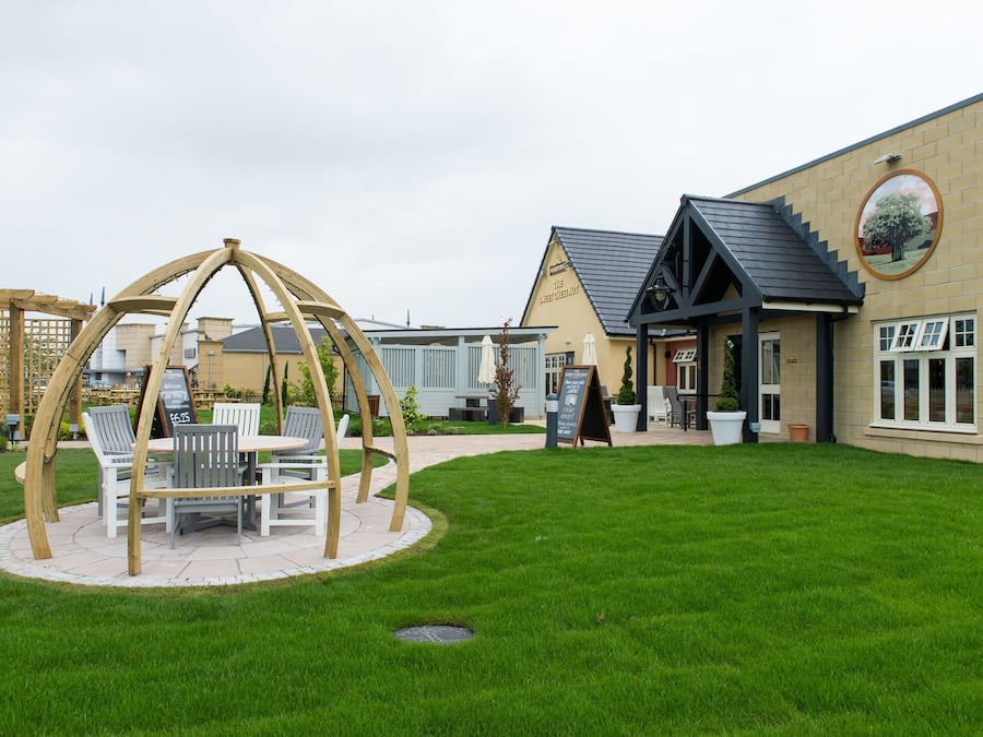 A building with a circular wooden structure in the center, surrounded by a well-maintained lawn.