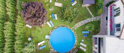 An aerial view of a backyard with a swimming pool, lounge chairs, and a stone pathway.