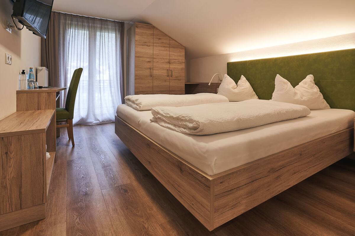 A modern hotel room with a wooden bed, a desk, and a television.