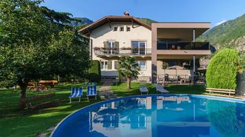 A two-story building with a pool, outdoor seating, and a mountain backdrop.