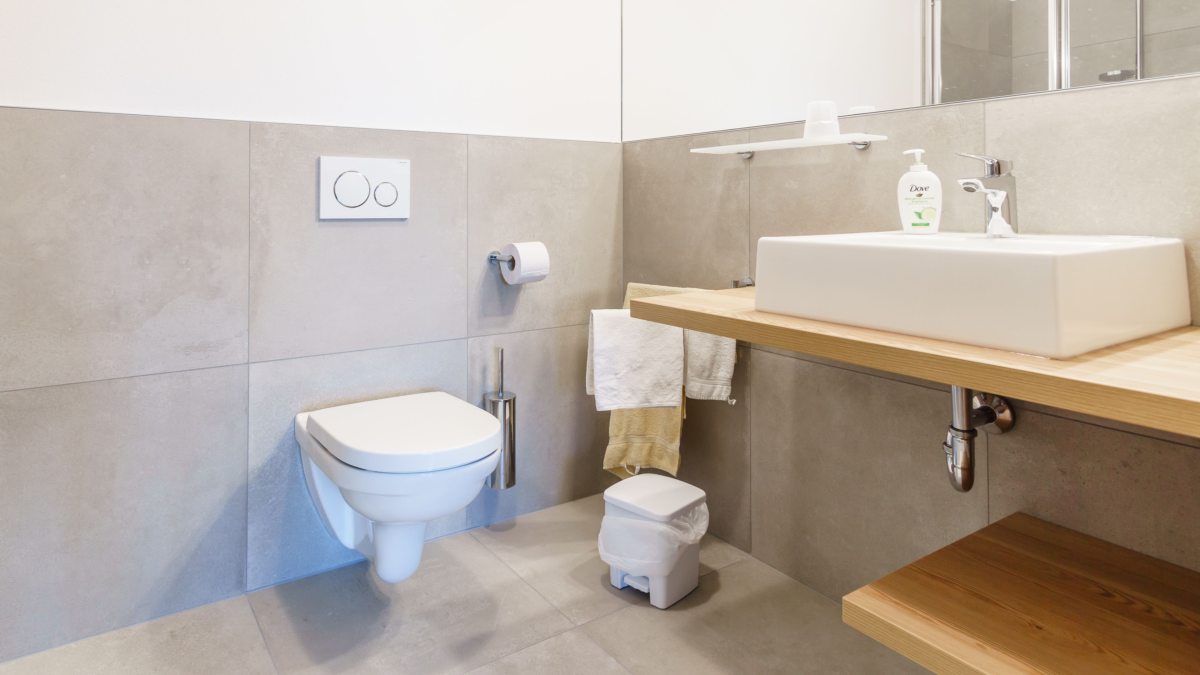 Une salle de bain moderne équipée de toilettes, d’un bidet, d’un lavabo et d’une petite poubelle.