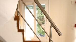 A staircase with wooden steps and metal handrails, leading to a door with a window above it. - Agios Nikitas View (Lefkada)