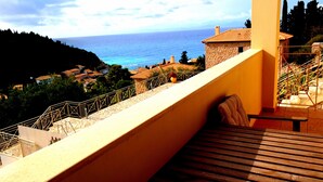 A balcony with a view of the sea and a stone building. - Agios Nikitas View (Lefkada)