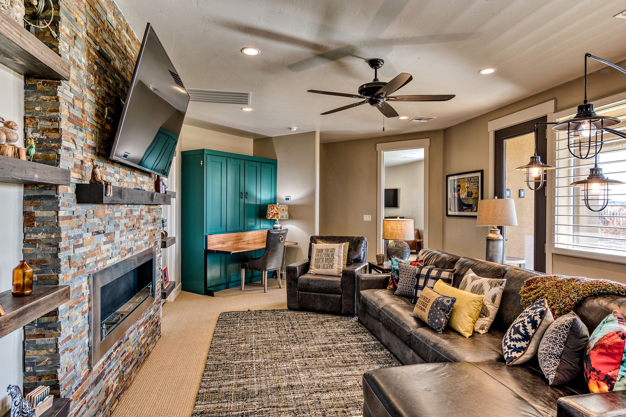 A cozy living room with a fireplace, a ceiling fan, and a comfortable seating area.