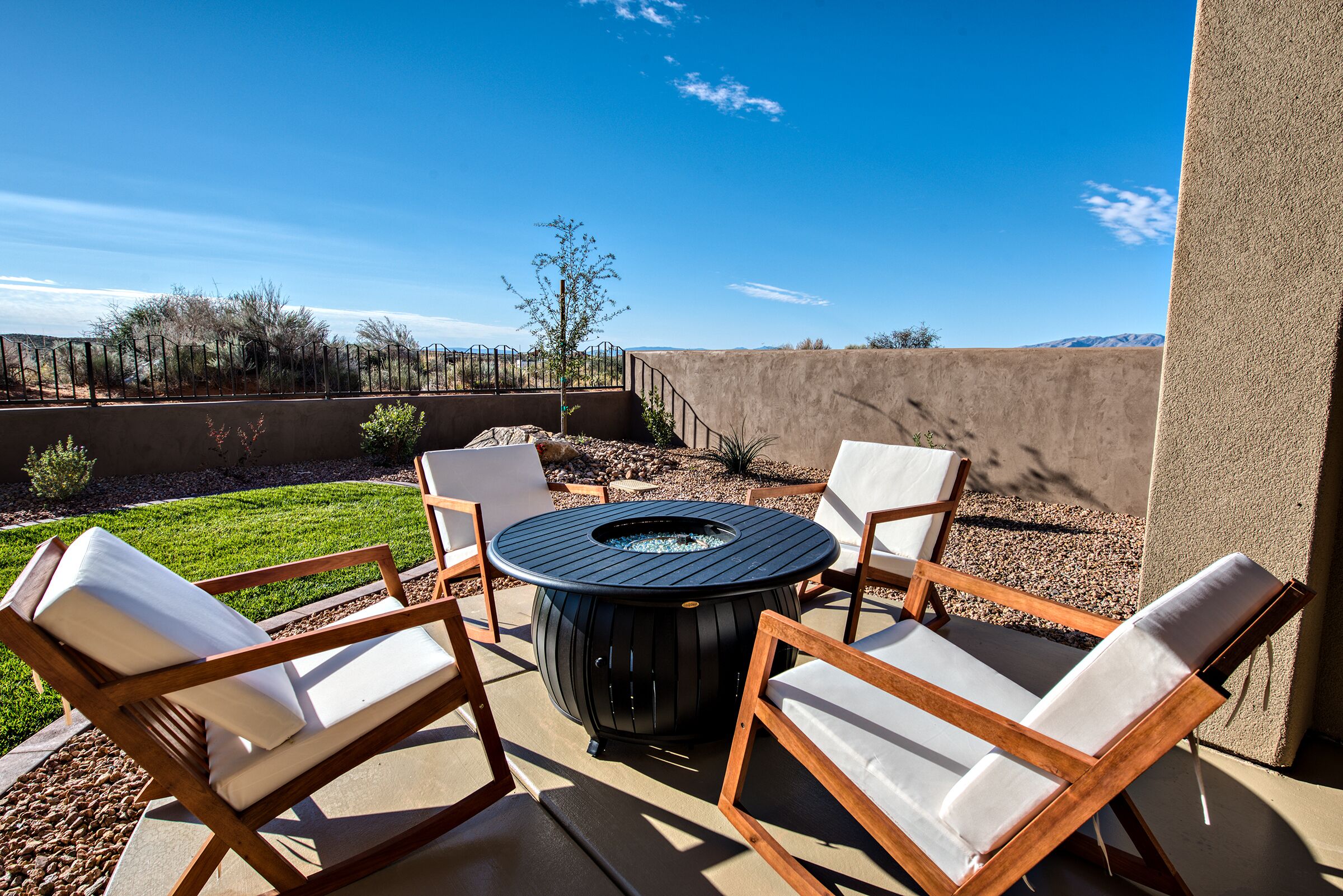 Une terrasse extérieure avec une table ronde et quatre chaises, entourée d’un petit muret et offrant une vue dégagée sur le paysage.
