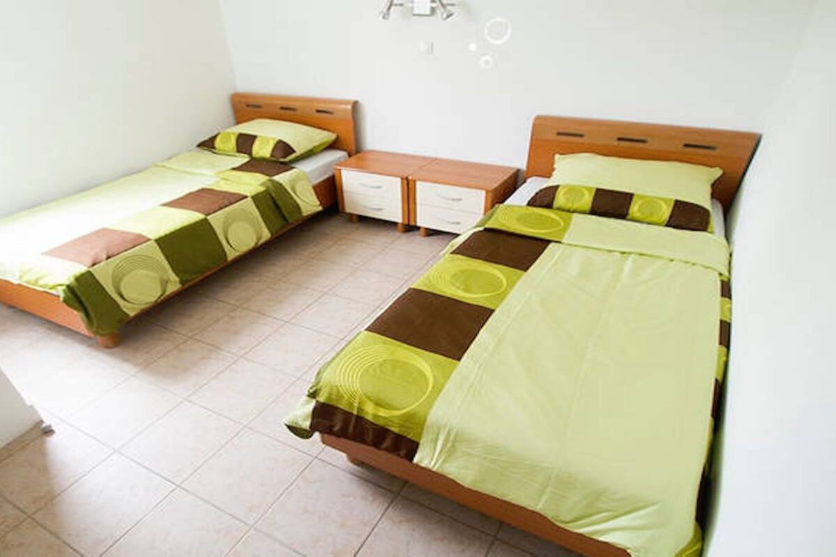 Una habitación con dos camas individuales, un pequeño tocador y una mesita de noche.
