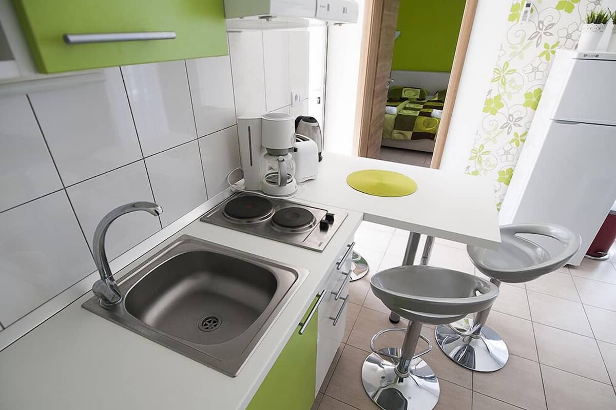 Una cocina moderna con un lavabo, estufa y un taburete pequeño.