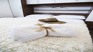 A neatly made bed with white linens and a straw hat placed on top. - Villa Mona (Rogoznica)