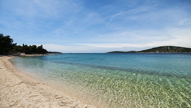 A clear beach with calm waters, sandy shore, and a distant hill. - Villa Mona (Rogoznica)