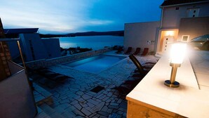 A rooftop pool area with stone flooring, a pool, and lounge chairs. - Villa Mona (Rogoznica)