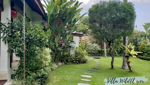 Um jardim exuberante com diversas plantas e um caminho de pedra que leva a um edifício.