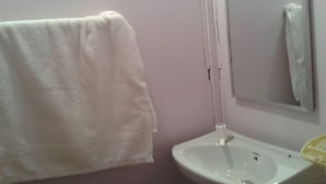 Un baño con un lavamanos blanco, un espejo y una toalla colgada en la pared.