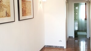 Ein Gang mit einer Kronleuchter, gerahmten Kunstwerken und einem roten Teppich mit Muster.