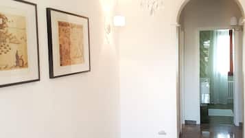Un couloir agrémenté d’un lustre, de tableaux encadrés et d’un tapis rouge à motifs.