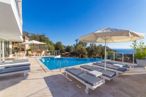 Una piscina al aire libre, sombrillas, sillones reclinables de piscina